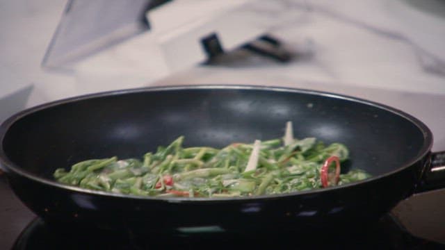 Water parsley pancake being cooked on an oiled frying pan