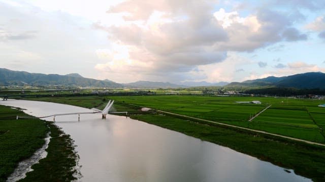 Serene river with a bridge and green fields