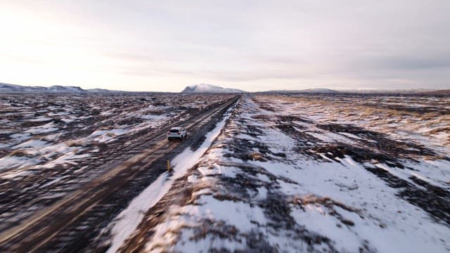 Car driving on a snowy road in a vast landscape