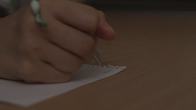 Handwriting on a small piece of paper with a pen in a dark room