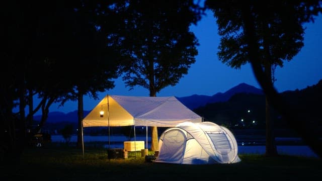 Evening campsite by river illuminated with soft lighting