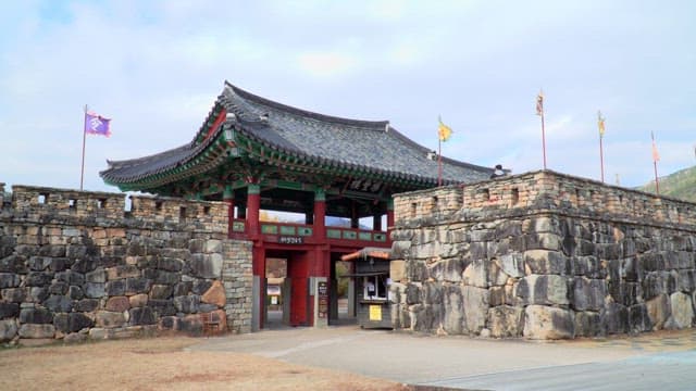 Entrance to an ancient Korean walled town with flags under a blue sky