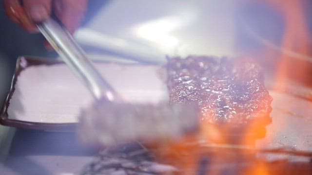 Grilled tteokgalbi being placed on a plate