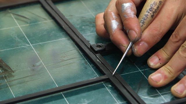 Handling a metal frame on a green grid cutting mat