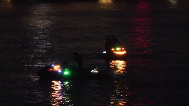 People riding jet skis with colorful lights at night