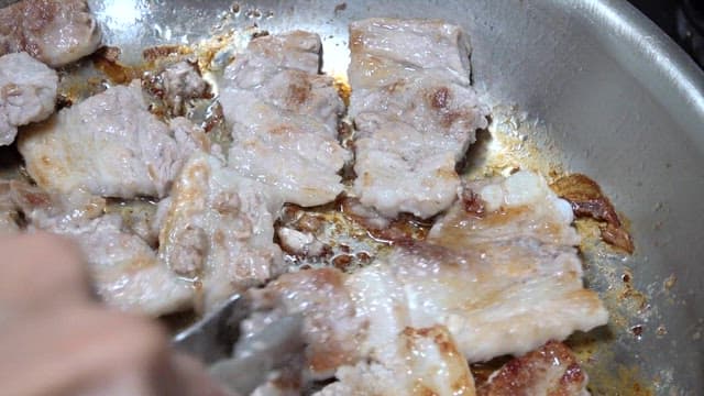Sizzling pork belly in a stainless steel pan