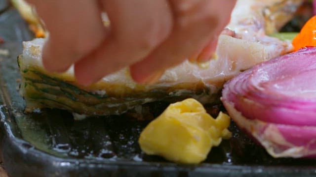 Butter melting on the grill as fish and onions cook