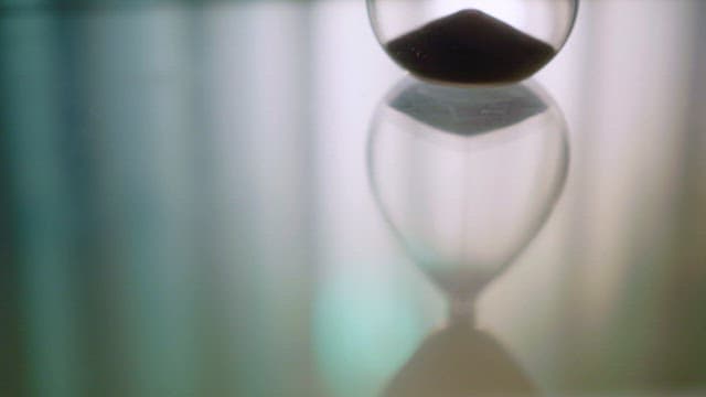 Hourglass with sand flowing slowly indoors