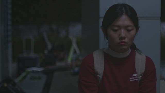 Woman sitting in a dark room and lowering her head with a sad expression