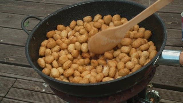 Stir-fried fish cakes cooked in a frying pan with a wooden spatula