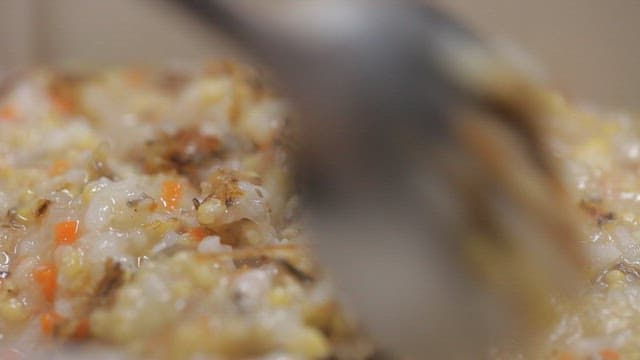 Stirring a pot of mixed rice porridge made of green eel goby with spoon