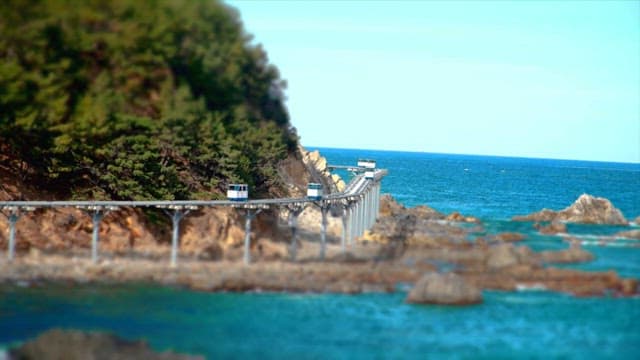 Coastal Monorail above the Rocky Shoreline with Waves on a Clear Day
