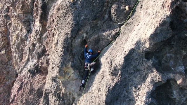 Climber Ascending a Rocky Cliff