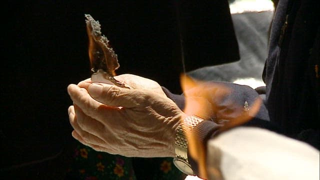 Elderly people lighting paper for religious ceremony