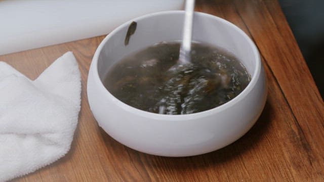 Warm seaweed soup with beef in a white soup bowl on a wooden table