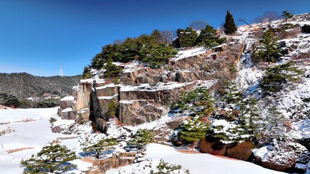 Snow-Covered Rocky Cliff Against Blue Sky