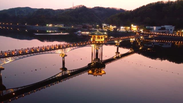 Illuminated bridge over calm river at night