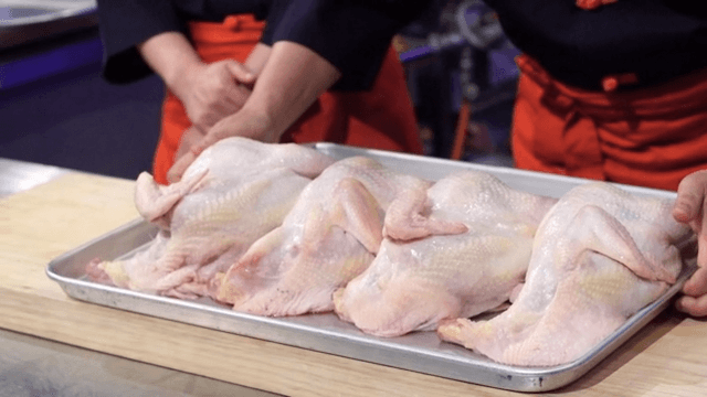 Chefs preparing raw chickens on a tray