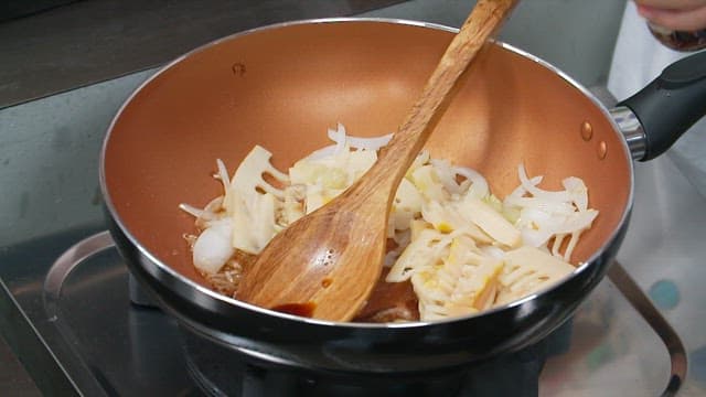 Adding soy sauce to the skillet with the chopped bamboo shoot