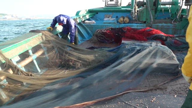 Fishermen preparing nets on a fishing boat at sea