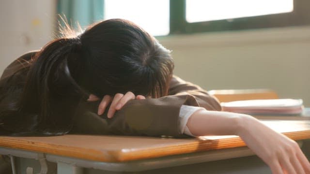 Student resting on a desk in a classroom