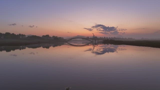 Calm river at sunset with a bridge