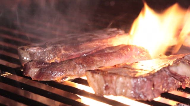 Juicy steaks grilling over open flames