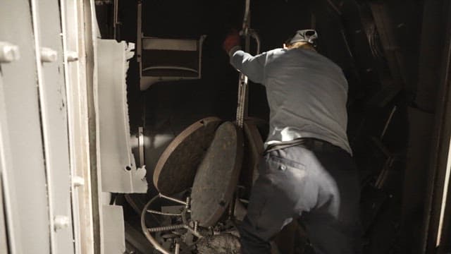 Worker putting metal parts into container