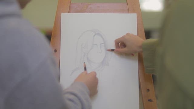 Two students painting a portrait in a classroom