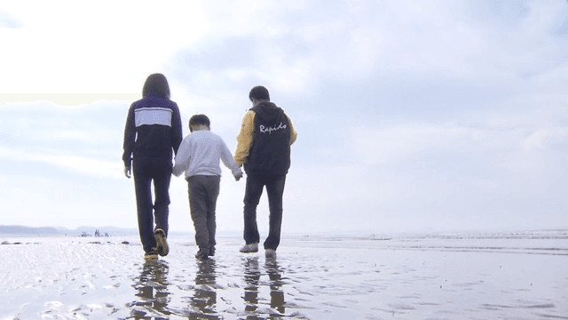 Family walking together on a beach with mudflats on a sunny day