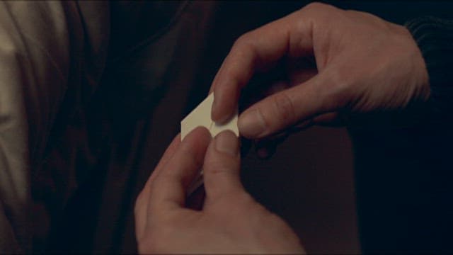 Hands Delicately Folding a Small Piece of Paper