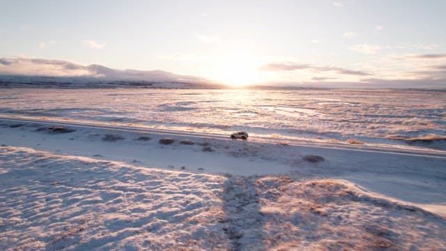 Car driving on a snowy road at sunrise