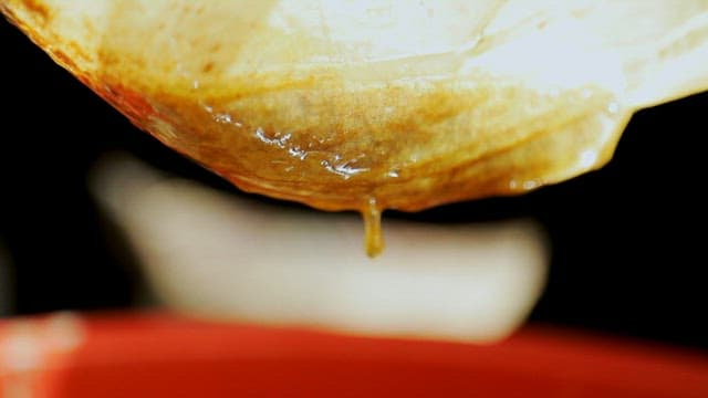 Pouring melted wax through a sieve cloth