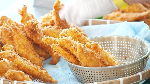Sorting freshly fried crispy fish fillets in the basket
