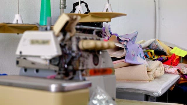 Old sewing machine surrounded by colorful fabrics in a workshop