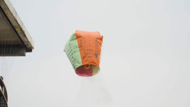 Sky lanterns floating against pale sky