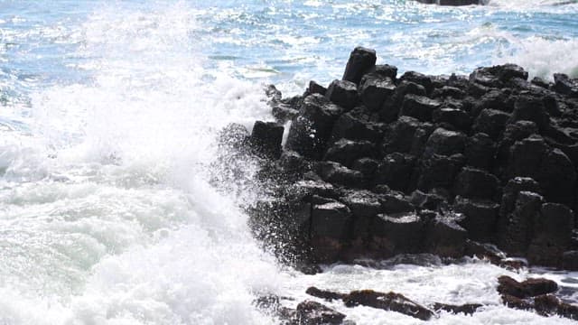 Waves crashing into the columnar joints of a rocky shoreline