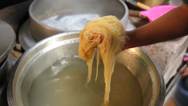 Hand preparing noodles in a pot