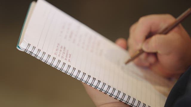 Person Writing in Notebook