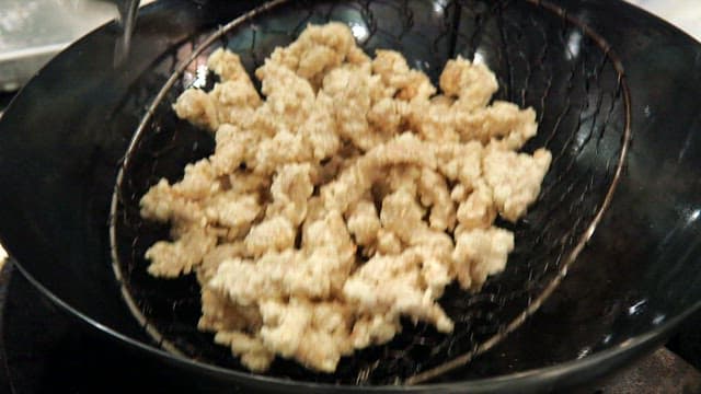 Frying meat in hot oil in a wok in the kitchen