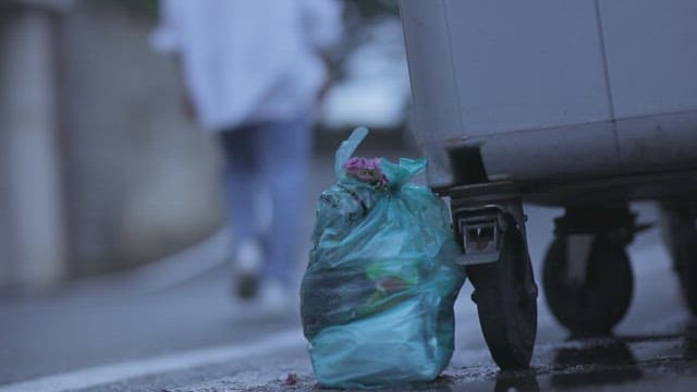 Bouquet of flowers thrown away in a garbage bag in front of a garbage dump
