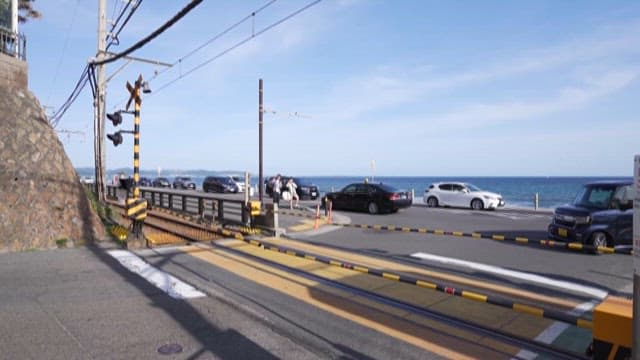 Train passing by a crossing near the sea on a sunny day