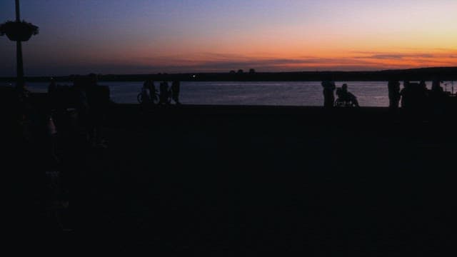 At the riverside at twilight, people enjoy a peaceful evening