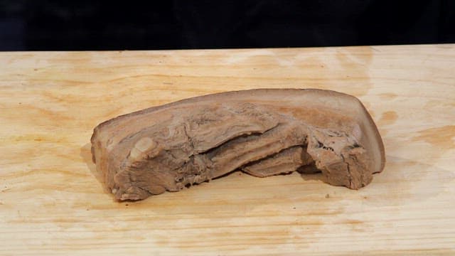 Slicing boiled pork slices on a wooden board