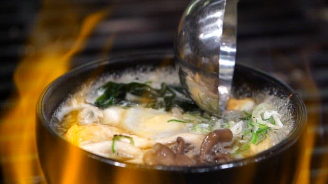Soup dish boiling in a pot on a stove with a flame