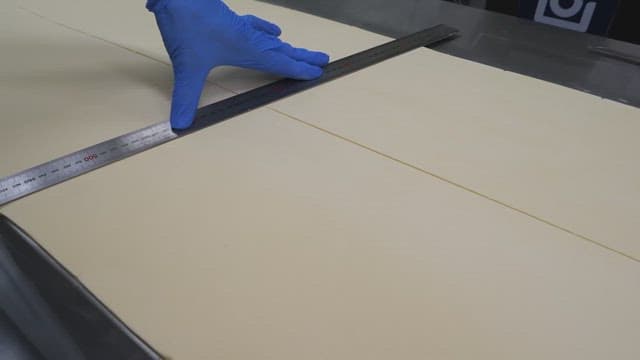 Worker in gloves cutting dough precisely with a ruler in an industrial kitchen setting