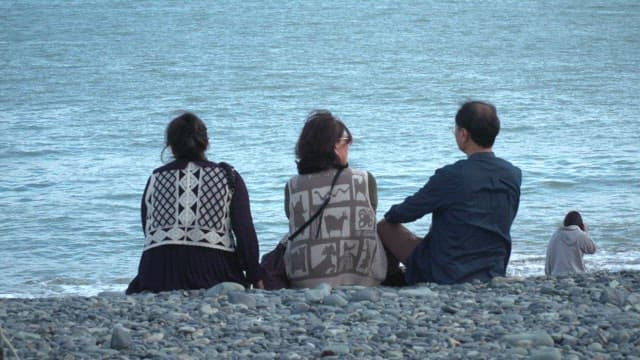 Family sitting by the sea on a pebble beach