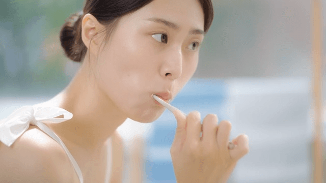 Woman brushing teeth in front of the mirror in the bathroom