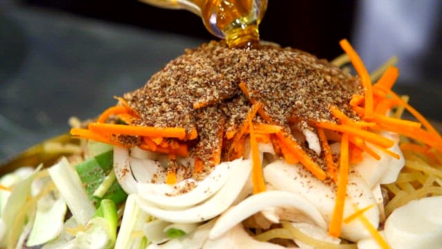 Pouring oil over vegetables with perilla seeds