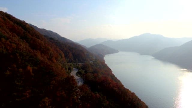 Autumn mountains with road next to tranquil lakeside